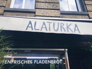 Schild am Eingang des Restaurants "Alaturka". Auf dem Fenster darunter wird mit ofenfrischem Fladenbrot geworben.